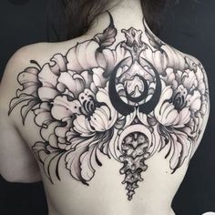 a woman's back with flowers and a crescent tattoo