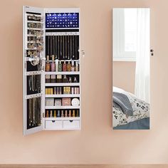 a white mirrored medicine cabinet sitting next to a bed in a room with pink walls