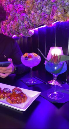 a man sitting at a table looking at his cell phone next to some desserts