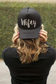 a woman wearing a black hat with the word wife written on it's front