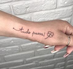 a woman's hand with a small tattoo on it that says, tudo papai