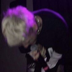 a man with blonde hair is singing into a microphone