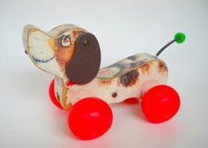 a toy dog with red wheels on a white background, it looks like he is going to ride in the same direction