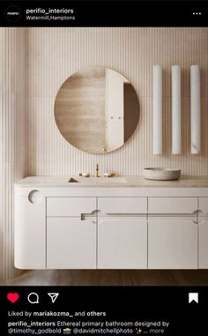 a bathroom vanity with a round mirror above it and two white cabinets below the sink