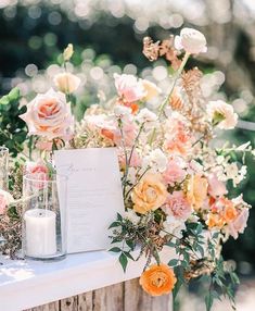 an arrangement of flowers and candles on a table with a menu in front of it