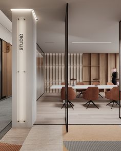 an office with glass partitions and wooden chairs in the center, along with a man standing at a table