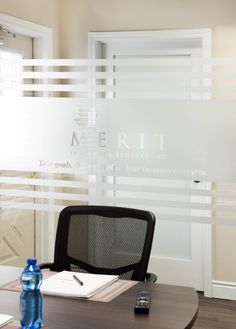 an office desk with a phone and water bottle on the table in front of it