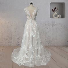 a white wedding dress on a mannequin in front of a wall with a vase