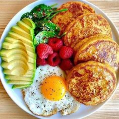 a white plate topped with eggs, fruit and pancakes