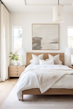 a bed with white linens and pillows in a bedroom next to two lamps on either side of the bed