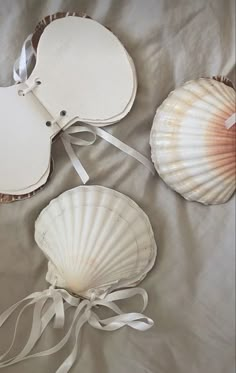 three seashells with ribbons tied around them on a bed