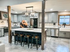 a man is standing in the middle of a large kitchen with an island and bar stools