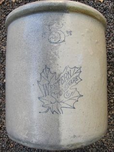 an old metal can with writing on it sitting on the ground next to some gravel