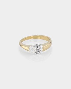 a yellow gold ring with an oval shaped diamond in the center, on a white background