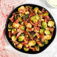 brussel sprouts with bacon in a black bowl next to a pink towel