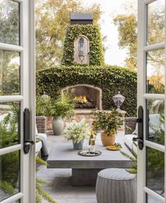 an outdoor fireplace is surrounded by greenery and potted plants