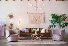 a living room with couches, chairs and potted plants on the wall above them