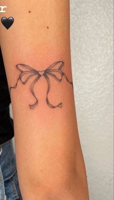 a woman's arm with a bow tattoo on it