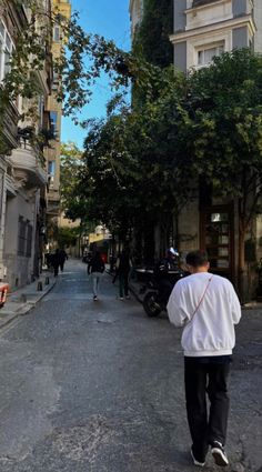 a man walking down a street next to tall buildings