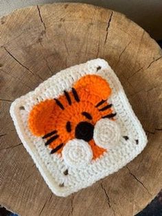 a crocheted tiger coaster sitting on top of a tree stump