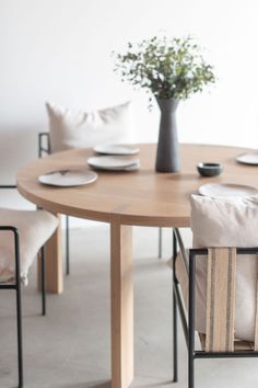 a wooden table with two chairs and a vase filled with flowers sitting on top of it