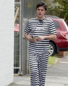 a man dressed in jail clothes walking down the street