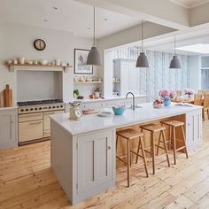 a large kitchen with wooden floors and an island in the middle, along with two bar stools