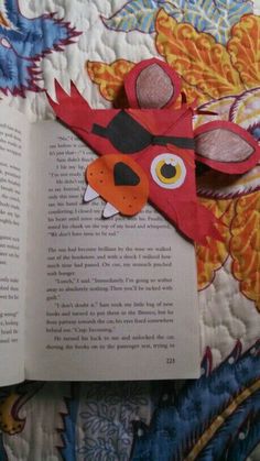 an open book with paper cut out of it's face on top of a quilt