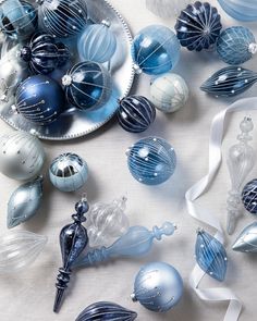 blue and white glass ornaments on a table with ribbon around them, including an ornament