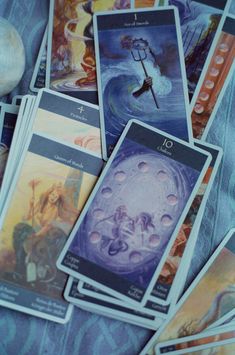 several tarot cards are laying next to an onion on a blue cloth with white writing