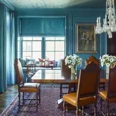 a formal dining room with blue walls and wooden furniture, chandelier hanging from the ceiling