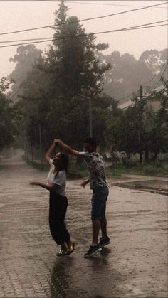 two people are playing in the rain on their skateboards