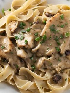 a white plate topped with pasta covered in mushroom sauce and garnished with parsley