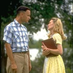 a man standing next to a woman in a yellow dress and holding a binder