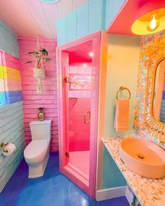 a bathroom with pink, blue and yellow colors on the walls next to a white toilet