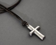 Handsome Stainless Steel cross pendant placed on a thick leather cord.    Antique Brown Leather cord from Spain measures 2mm thick.   The cross is knotted on the leather cord in the center.   Cross Size: 1 1/4 inches long, 3/4 inch wide, 1/4 inch thick. CHOICE OF:  Stainless Steel Lobster Clasp with open link chain for adjustment  OR  Double knots  - adjustable (like you see on other leather necklaces) Fits between 20 inches up to 22 inches long with the lobster clasp, up to 28 inches long with Adjustable Brown Cross Necklace, Cross Necklace Mens, Necklace Man, Leather Necklaces, Stainless Steel Cross Pendant, Lubbock Tx, Necklace Mens, Mens Necklace, Necklace Cross