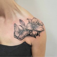 a woman's shoulder with a butterfly and flower tattoo on it, in black and white