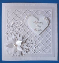 a wedding card with a heart and flower on it's side, sitting on a blue background