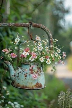 an old watering can with flowers in it