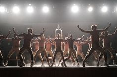 a group of men standing on top of a stage with their arms in the air