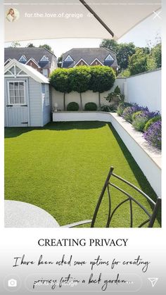 a small backyard with green grass and purple flowers