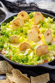 a skillet filled with tortilla shells, lettuce and cheese next to crackers