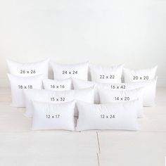 six white pillows with numbers on them sitting in front of a white wall and floor