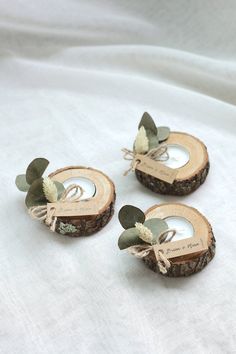 three pieces of wood with leaves on them sitting on a white cloth covered tablecloth