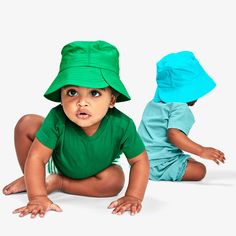 two small children wearing matching green and blue hats