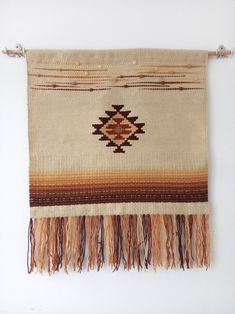 an old rug hanging on the wall with some tassels and fringes around it