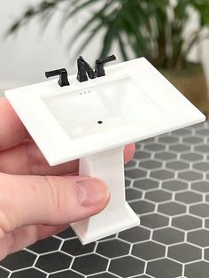 a miniature sink and faucet are in someone's hand