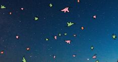 the night sky is filled with stars and colorful paper cranes flying in the air above trees