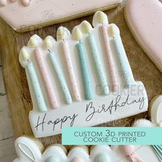 a birthday cake with candles and cookies on the table next to it is a happy birthday card that says, custom 3d printed cookie cutters