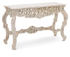 an ornate white console table with carved wood